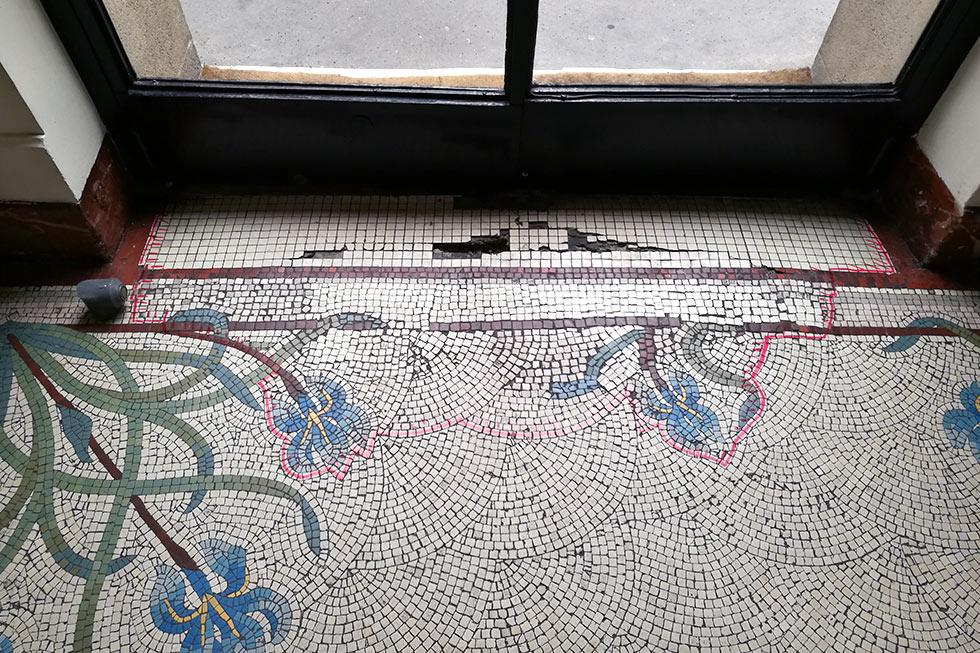 entrée en mosaïque dégradée par les infiltrations d'eau et les passages